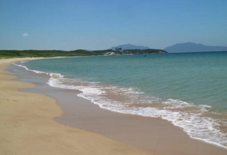 A bowl of udon noodle soup topped with green onions, tempura, beef, and a fish cake, served alongside onigiri rice balls wrapped in seaweed.