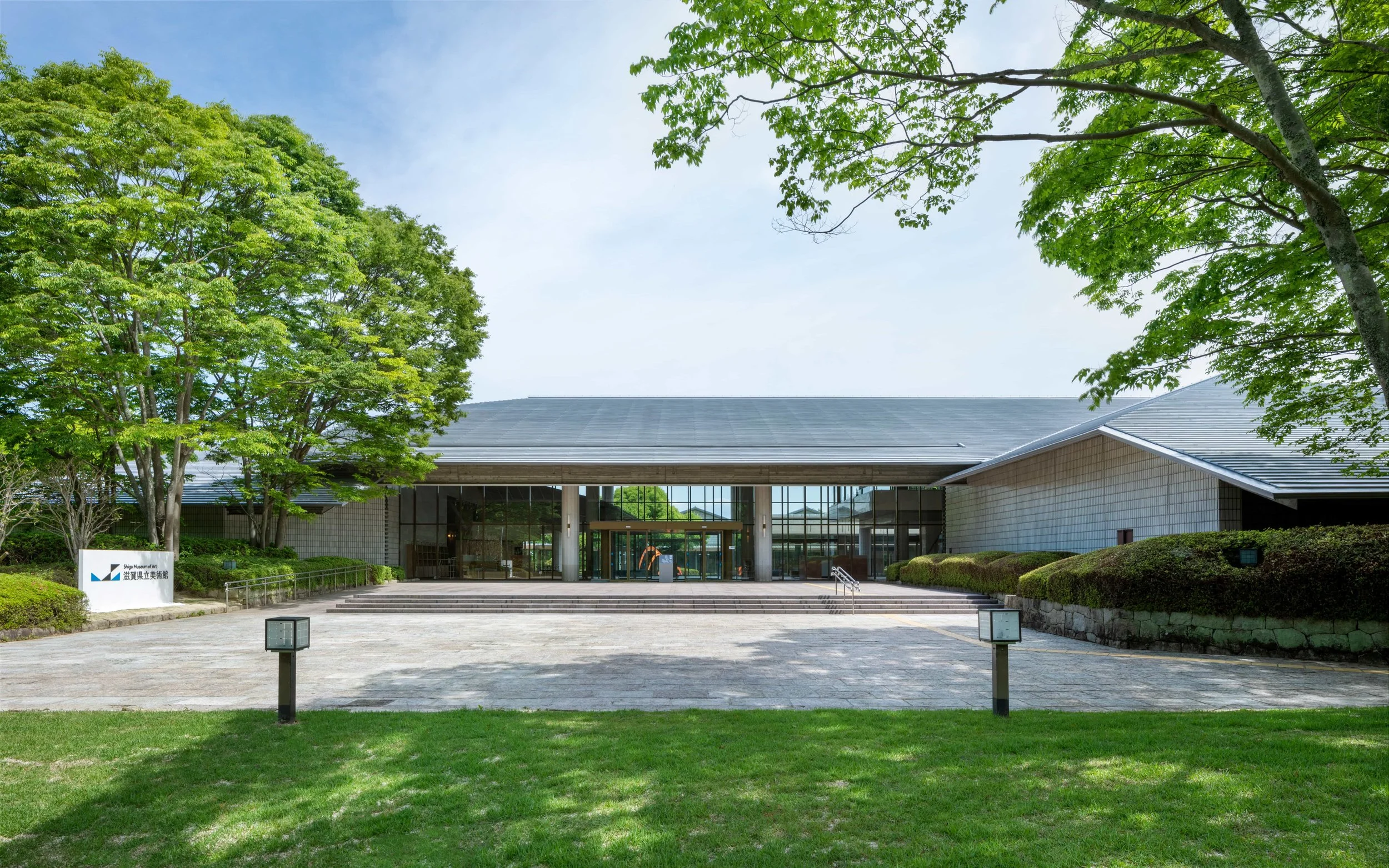 The serene exterior of Shiga Museum of Art framed by lush green trees — a hidden gem for art lovers in Ōtsu, Shiga.
