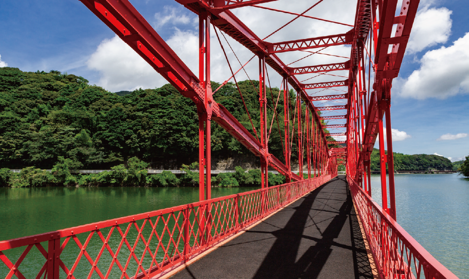 A modern building with glass doors and windows, decorated with flags and signs, including a cartoon tiger mascot wearing a white hat and cape, outdoors on a sunny day with trees in the background.