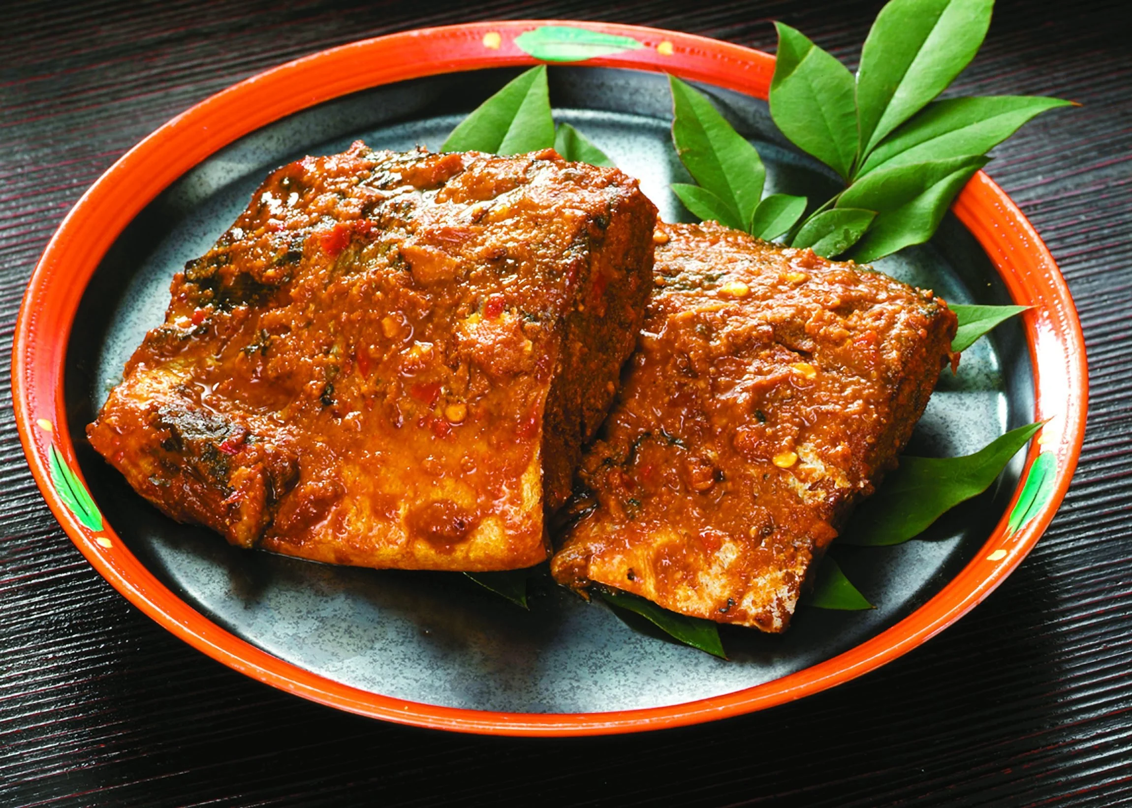 Mackerel simmered in fermented rice bran paste (nukadaki), served on a traditional orange-rimmed plate — a signature dish of Kokura, Kitakyushu.
