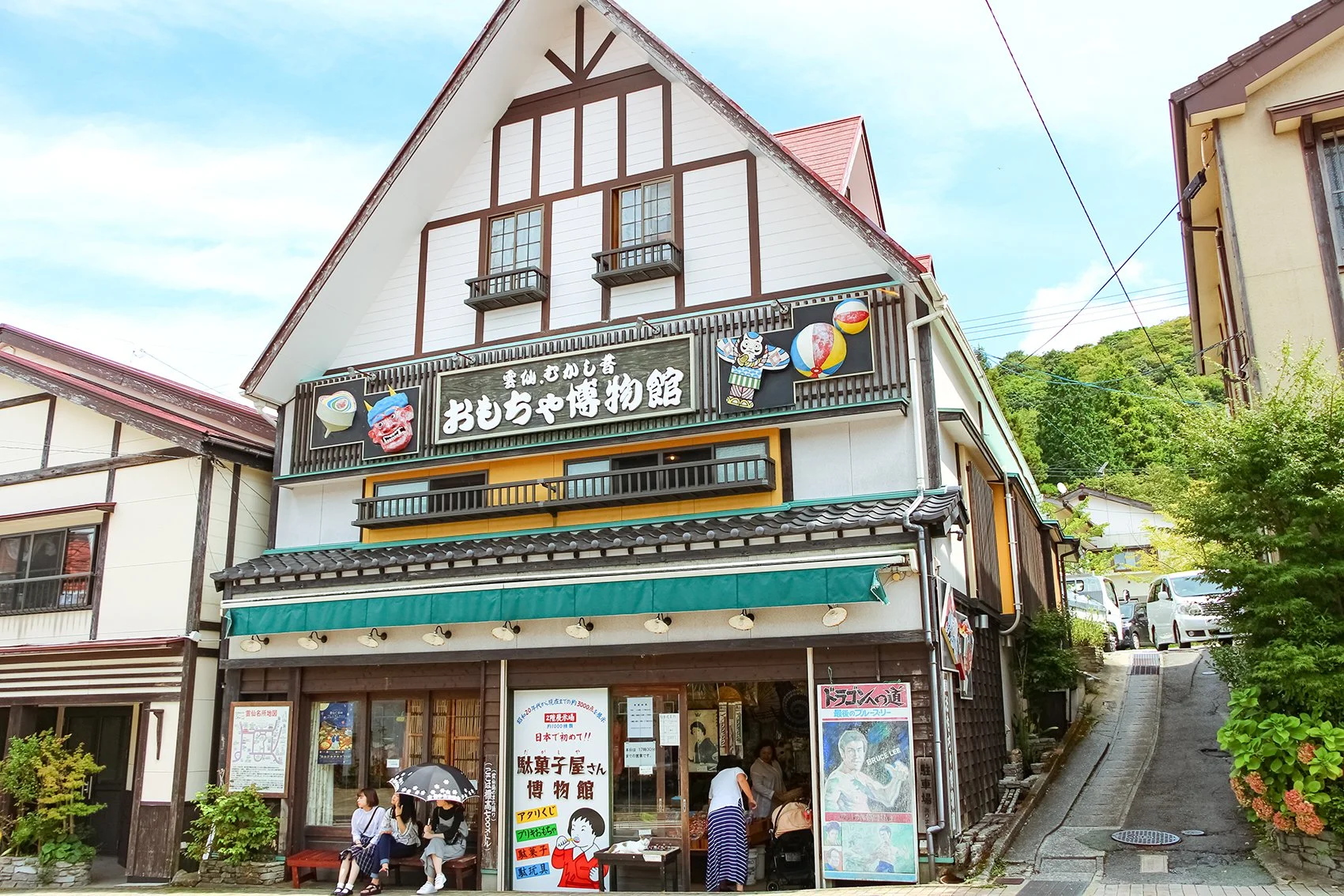 Retro timber-framed Unzen Toy Museum storefront on a sloping street in Unzen Onsen, evoking Japan's nostalgic Showa era