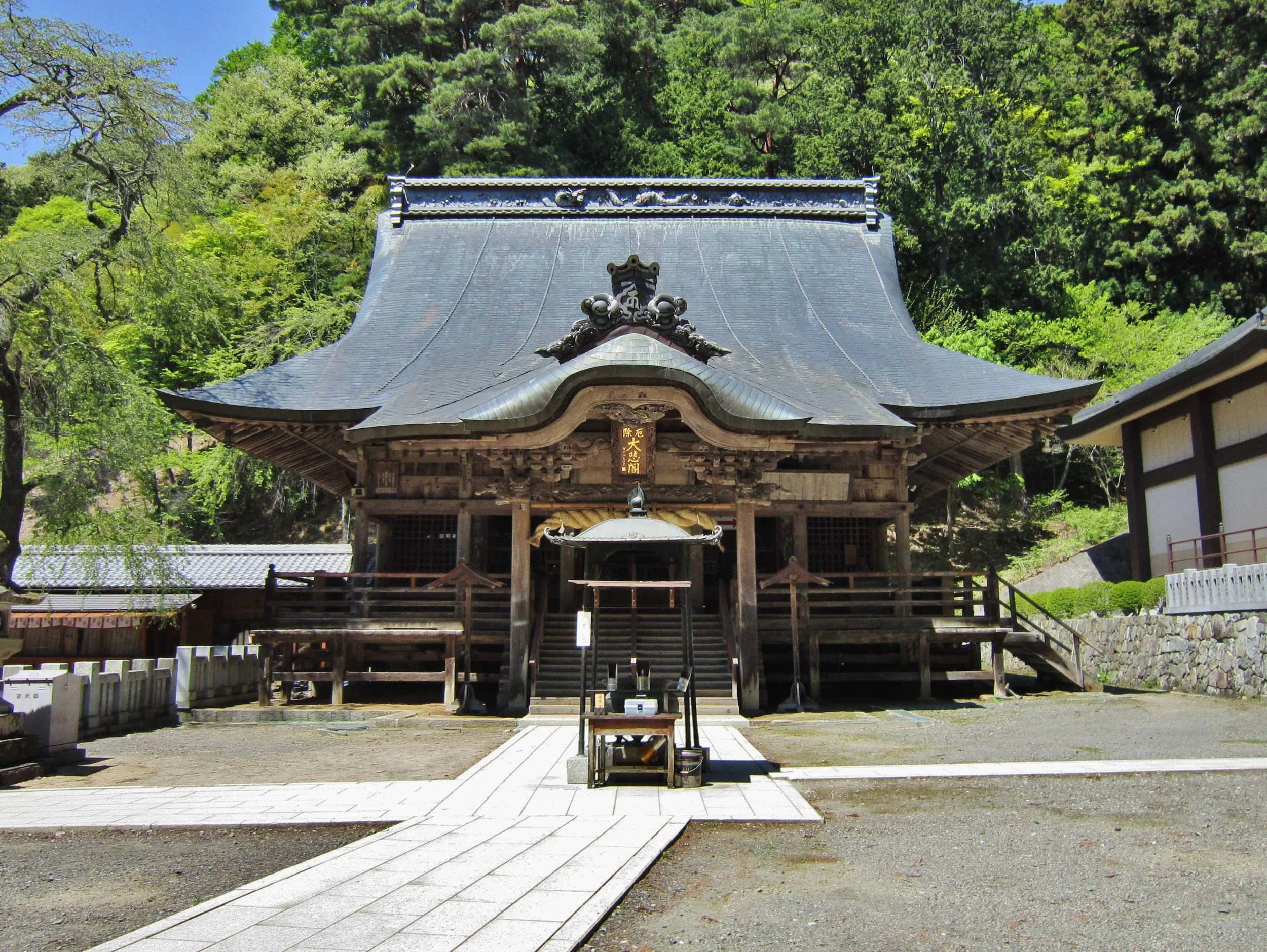 Weathered wooden main hall of Gofukuji Temple in Matsumoto, framed by a beech forest on Mt. Hachibuse — a quiet Shingon sanctuary of sacred art.