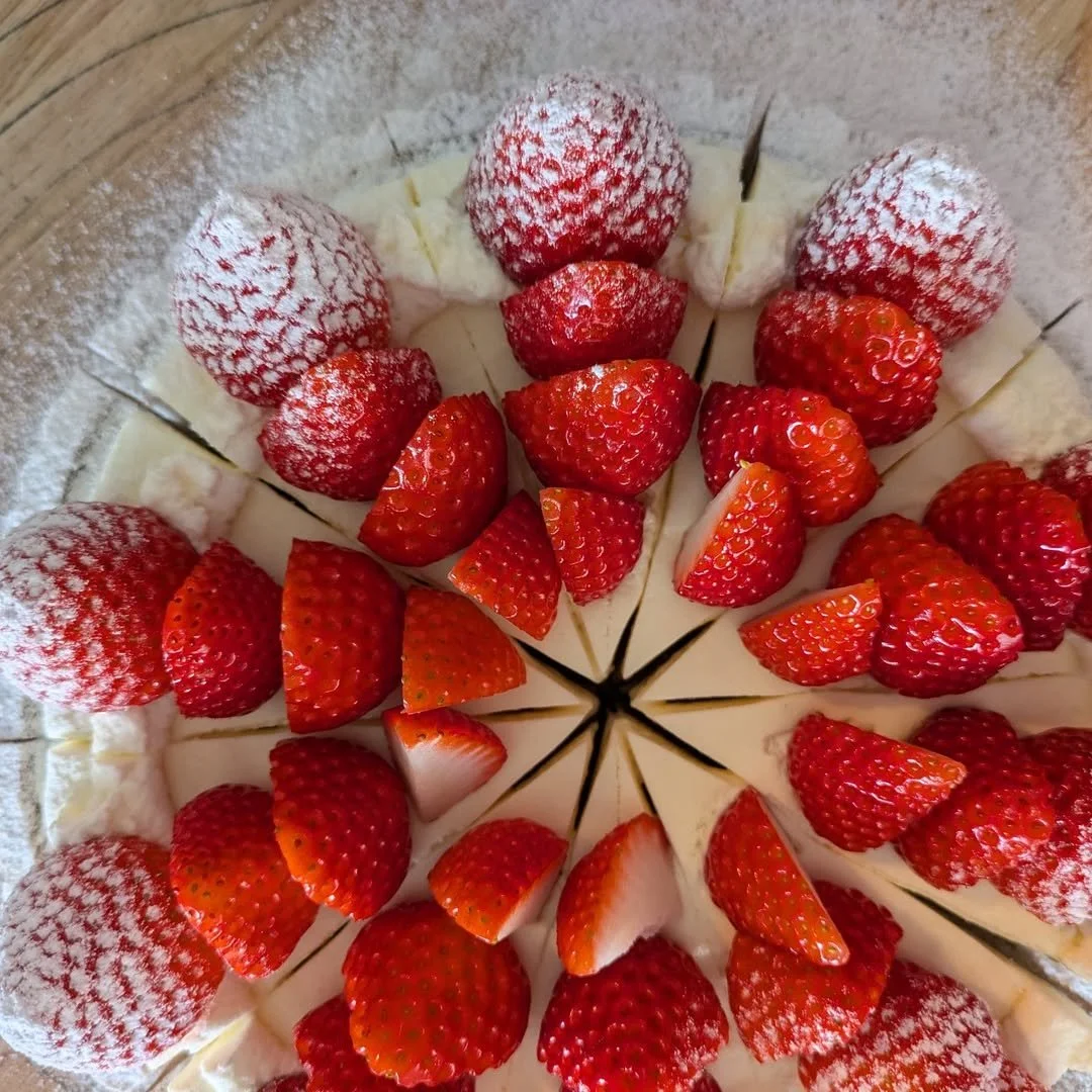 Close-up of a sliced strawberry cake with fresh strawberries and whipped cream.