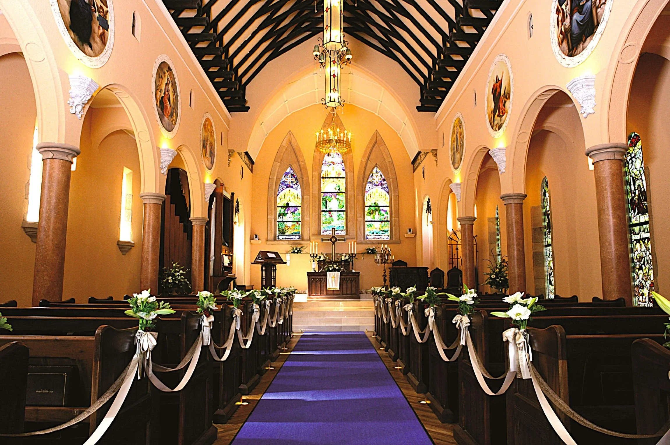 Sunlit English-style chapel interior at Kawana Stained Glass Museum in Izu — antique British stained glass, wooden pews, and a serene ceremonial atmosphere.