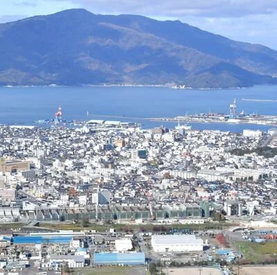 Elevated view of Tsuruga, a historic port town in Fukui Prefecture, with its harbor, cityscape, and surrounding mountains.