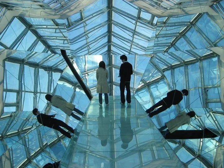 Two visitors stand on a mirrored glass walkway inside Kankaku Museum, Miyagi — a sensory art space where reflection and stillness meet.