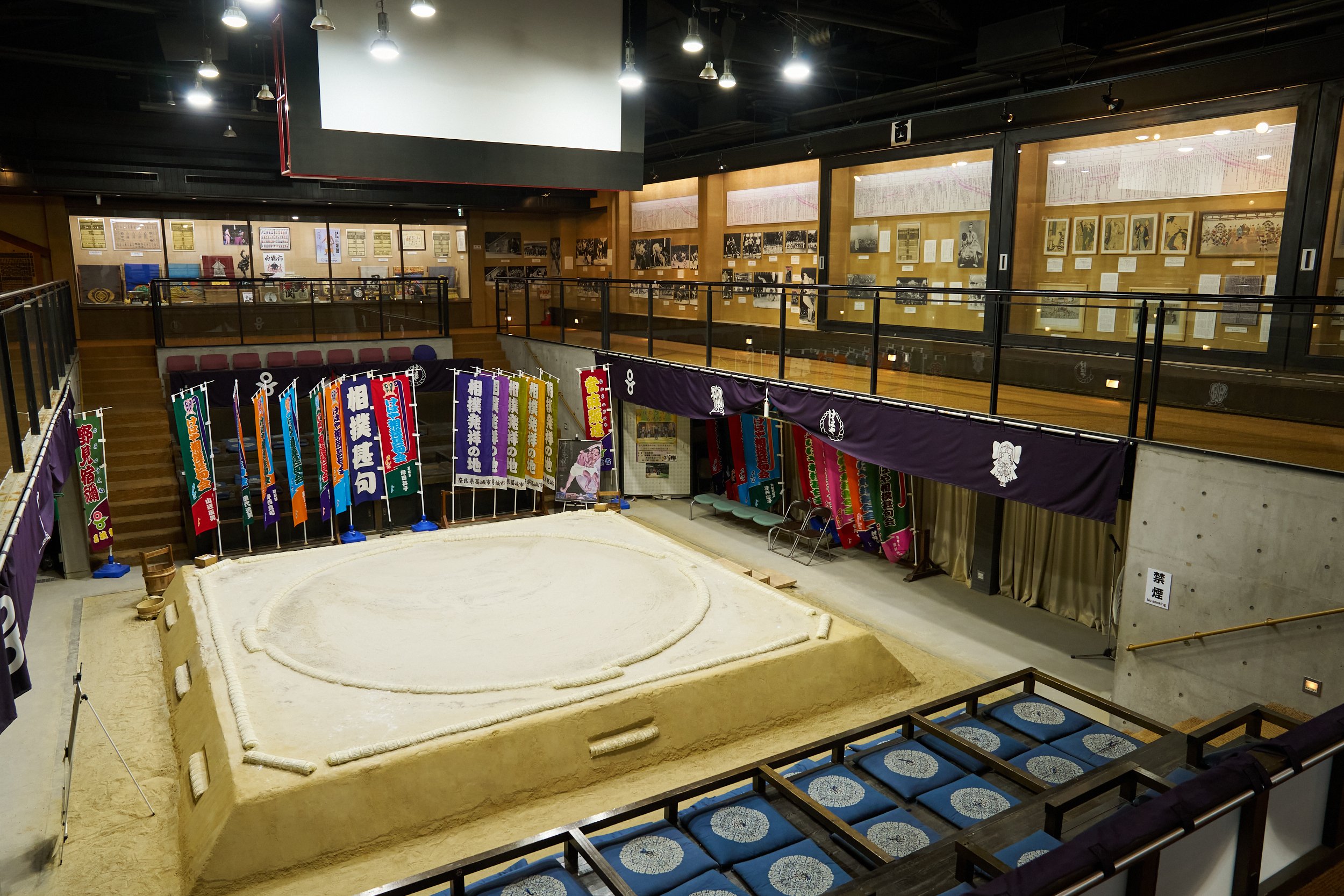 Full-scale sumo ring surrounded by colorful ceremonial banners inside Katsuragi Sumo Museum Kehaya-za, the legendary birthplace of sumo in Nara.