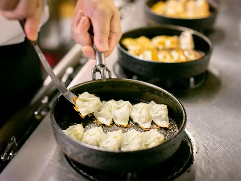 A modern building with glass doors and windows, decorated with flags and signs, including a cartoon tiger mascot wearing a white hat and cape, outdoors on a sunny day with trees in the background.