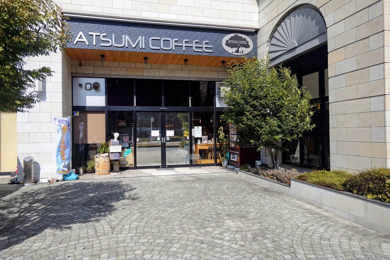 Exterior of ATSUMI COFFEE near Kokura Station in Kitakyushu — a specialty coffee shop and katsu restaurant with a welcoming stone courtyard entrance.