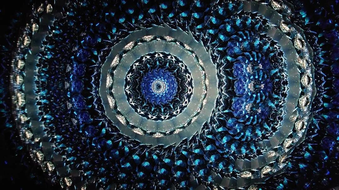 A dessert served in a tall glass with various toppings like fruit, beans, and cookies, viewed on a tray with a blurred background.