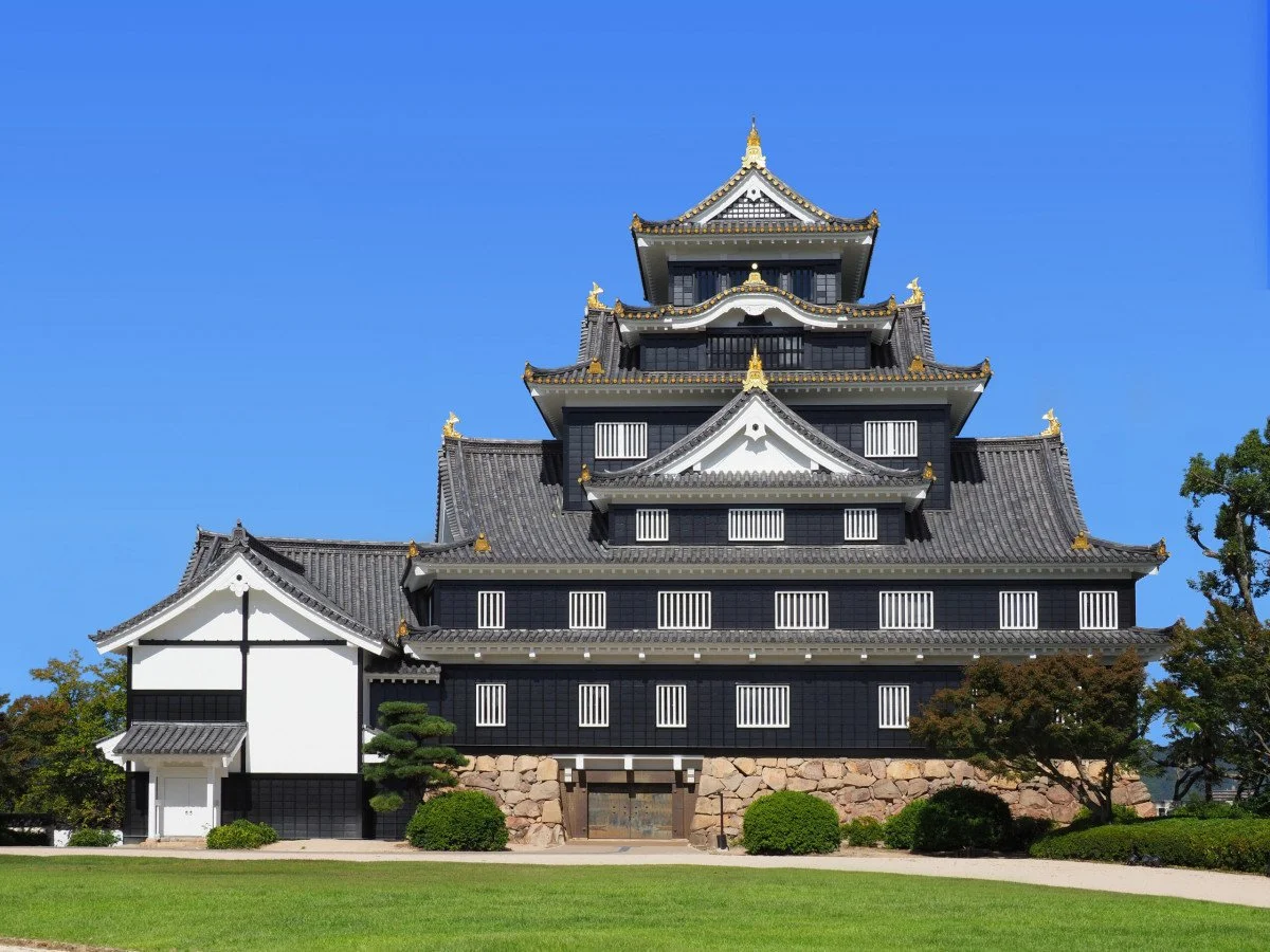 Okayama Castle's striking black exterior, nicknamed "Crow Castle," rising against a clear blue sky in Okayama City, Japan.