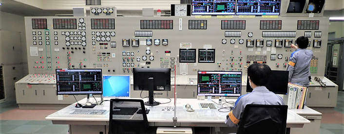 A staff member operating machinery inside Shin-Kokura Power Plant — an industrial facility tour experience in Kitakyushu, Kyushu.