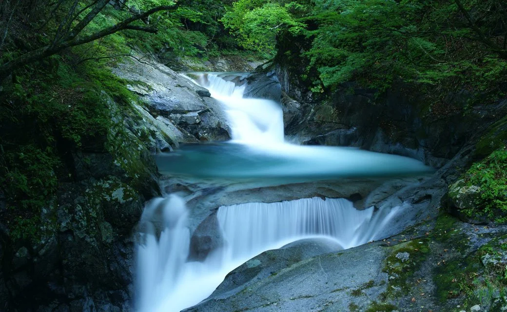 Silken waterfall cascading into a turquoise pool through a mossy granite gorge at Nishizawa Valley, Yamanashi — a hidden natural sanctuary in Japan.
