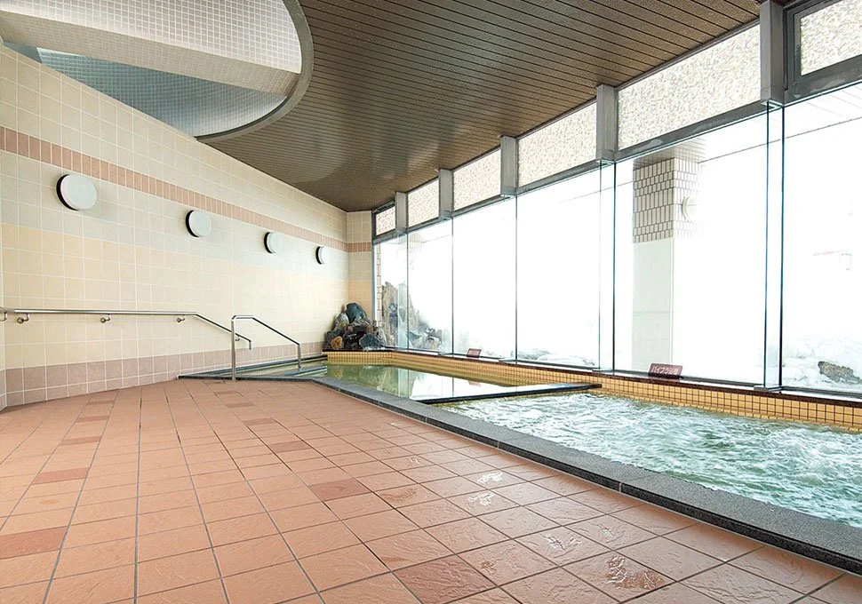 Sunlit indoor bath at Teshiogawa Onsen in Otoineppu, Hokkaido — quiet mineral pools by wide windows, a hidden northern retreat.