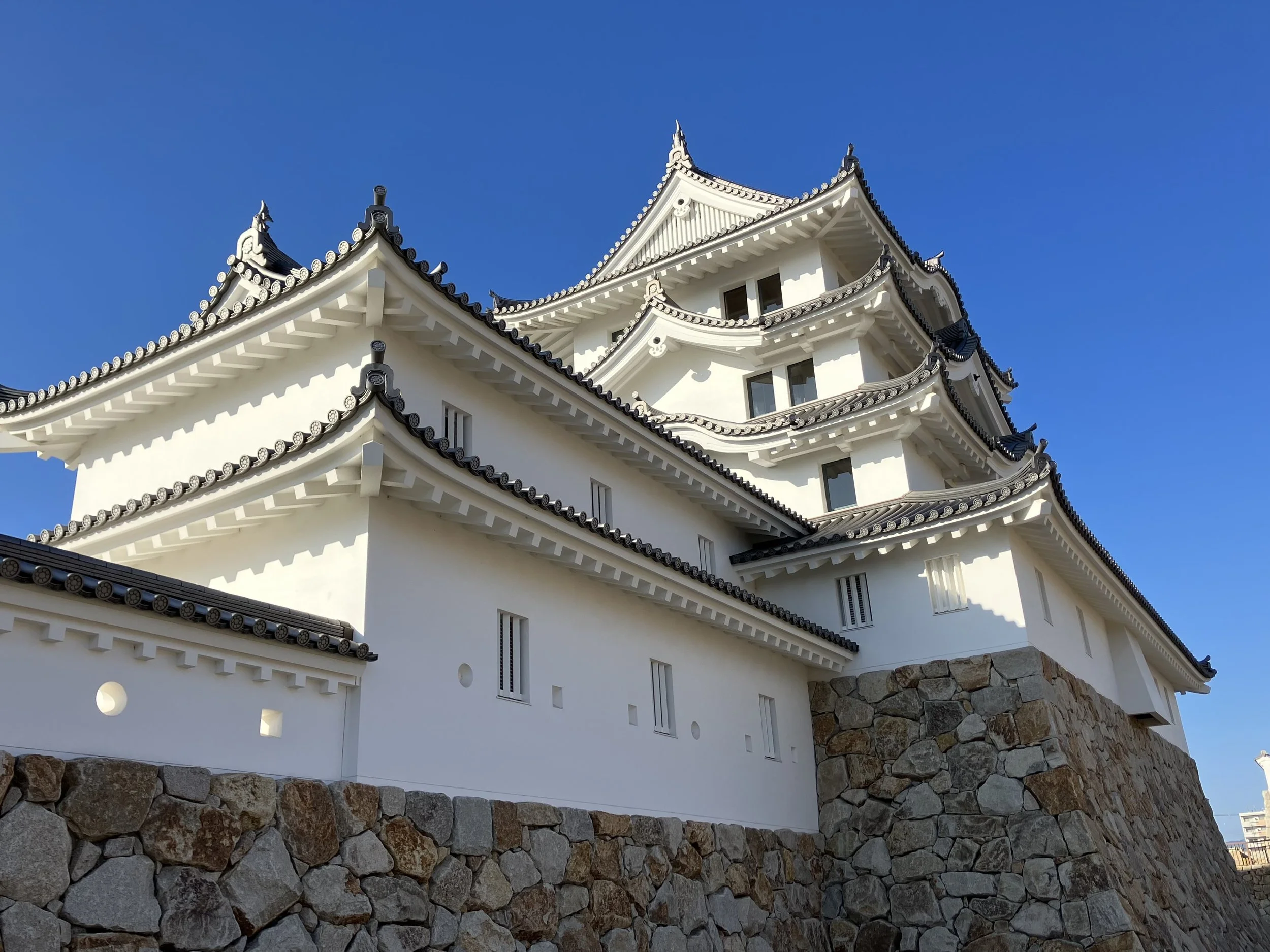 White multi-tiered Amagasaki Castle against a clear blue sky — a revived Edo-period fortress and family travel gem in Hyogo, Japan.