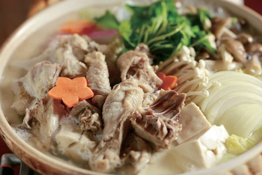 A traditional Japanese hot pot of shamo chicken simmered in clear broth with tofu, enoki mushrooms, and flower-cut carrots — a warming Northern Kanto specialty.