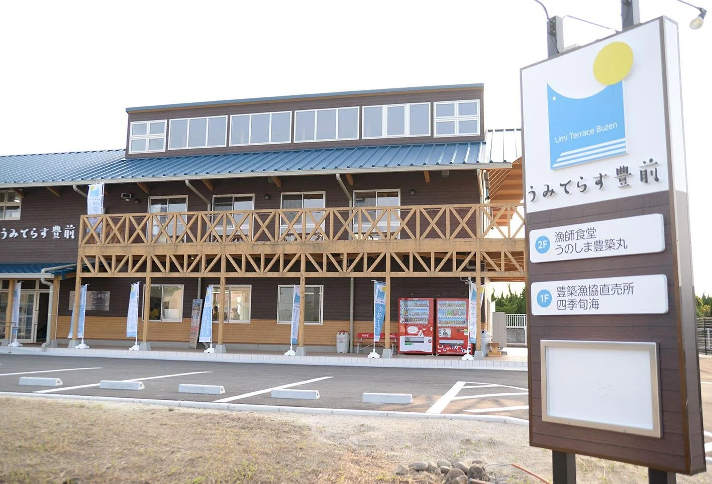 Umi Terrace Buzen exterior — a wooden two-story fishermen's market and seafood restaurant with a blue roof on the Buzen coast, Fukuoka.