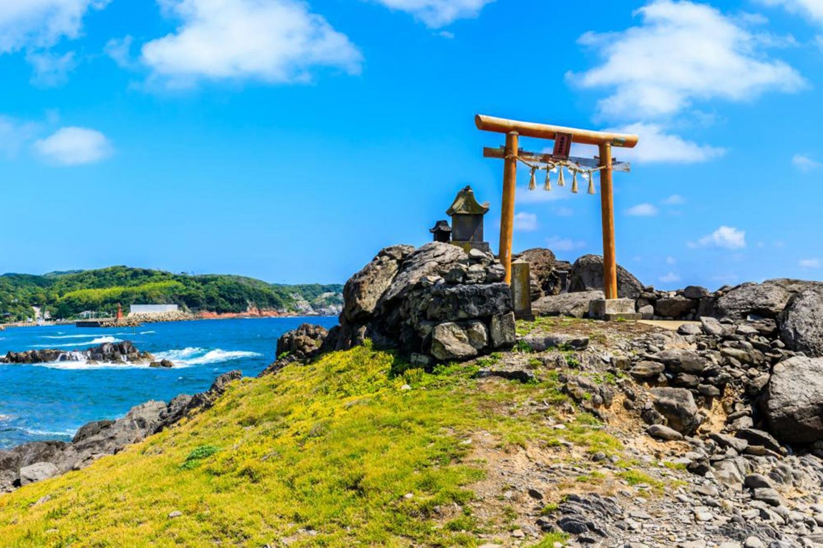 Wooden torii gate with sacred rope perched on the rocky Ryujinzaki promontory of Iki Island, overlooking the deep blue sea — a mystical sanctuary of the Dragon Snake God.