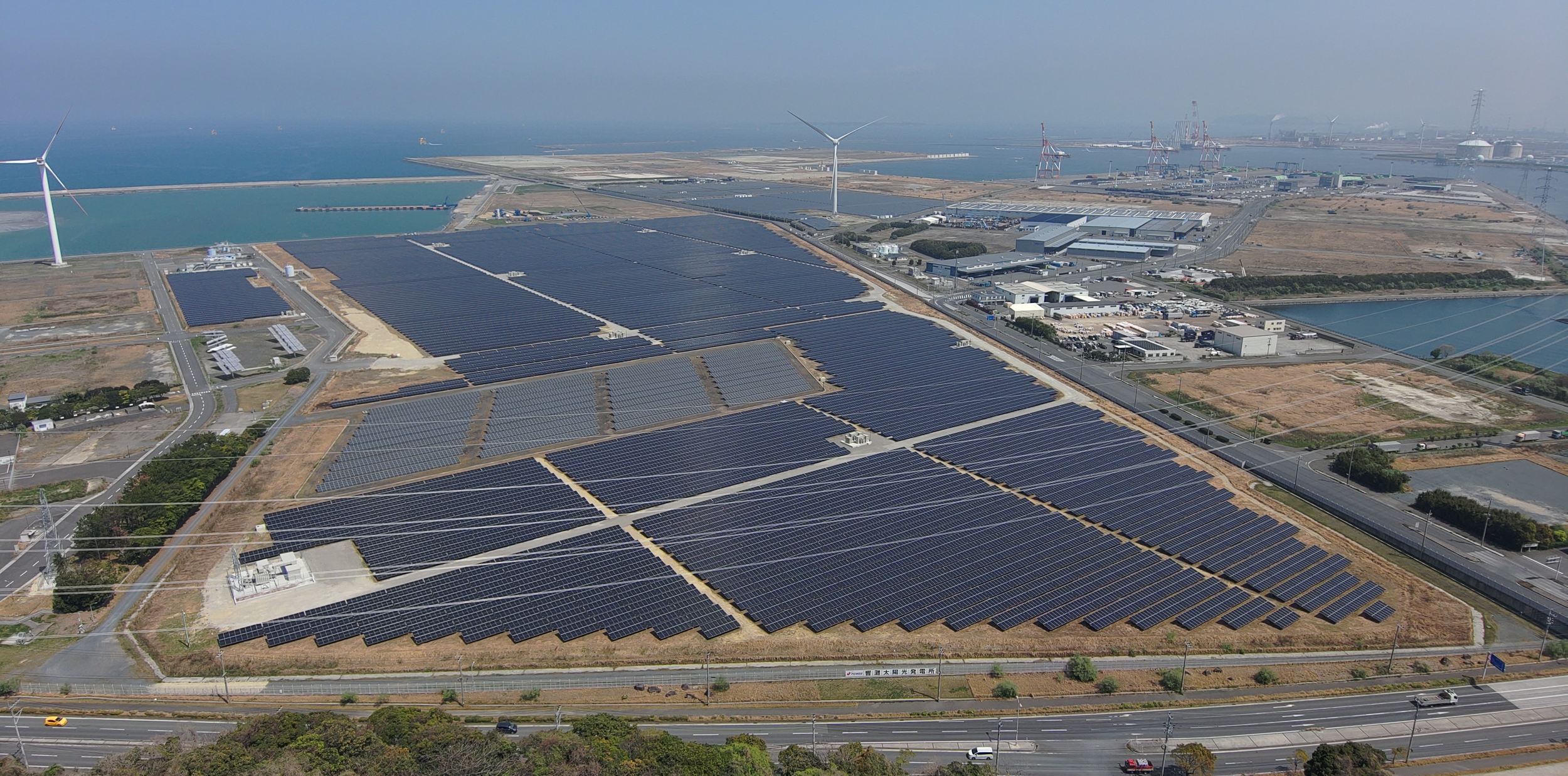 Aerial view of J-POWER Wakamatsu General Works in Kitakyushu — wind and solar energy facilities at an industrial research site in Japan.
