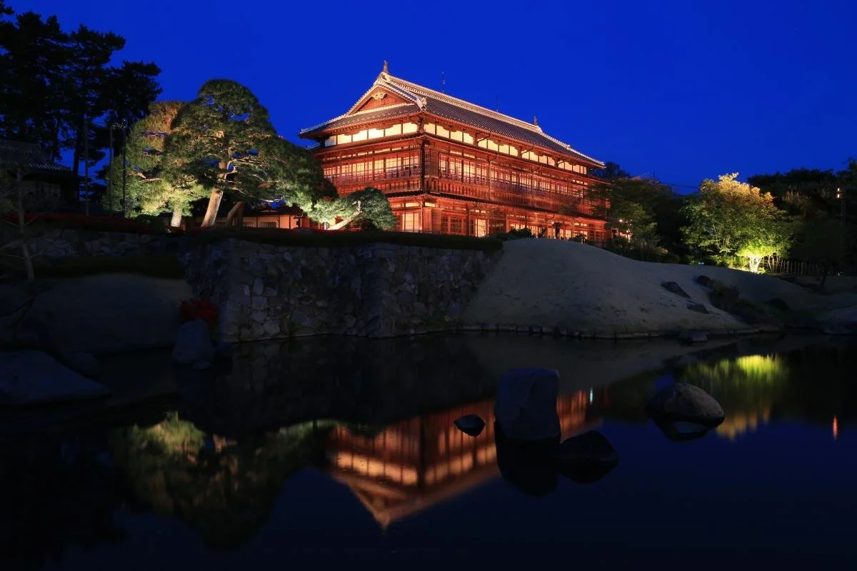 Rinkokaku's Meiji-era wooden main hall illuminated at night, reflected in the garden pond — a National Important Cultural Property in Maebashi, Gunma.