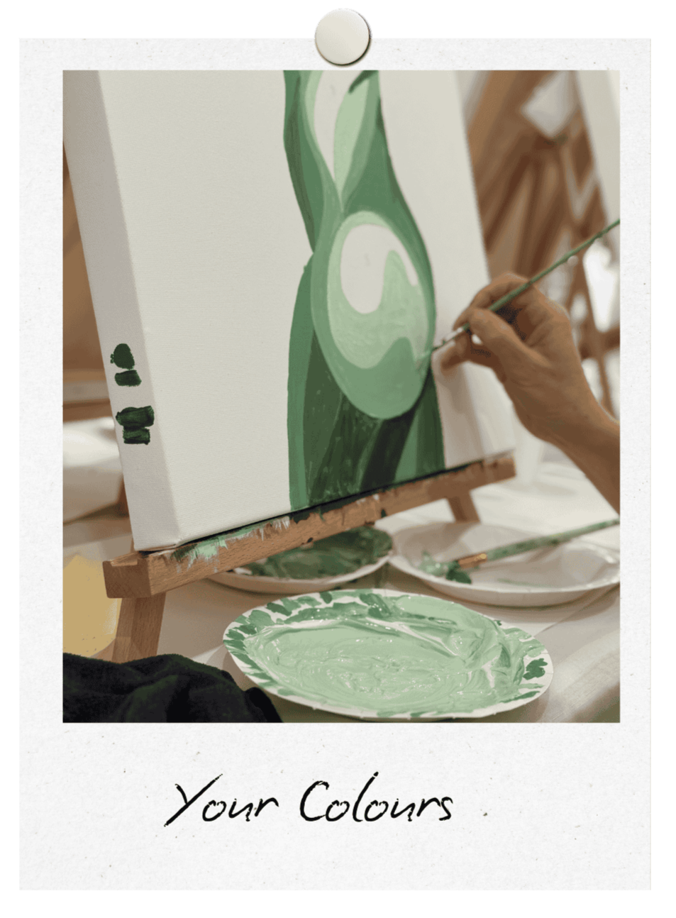 Custom Canvas of female body from the side showing hip and bum painted in shades of green at a hens part in Manly. There is a hand holding a brush painting the canvas with a paper plate covered in paint in the foreground.
