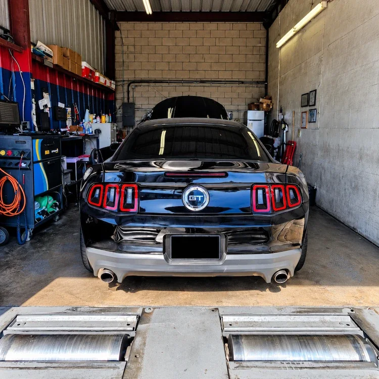 Rear of a black Ford Mustang GT inside the inspection bay at Hernandez Smog Check in Whittier, CA.