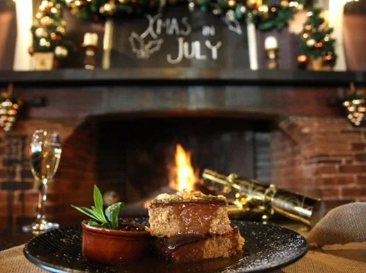 Christmas pudding, glass of champagne and christmas crackers in front of a fire