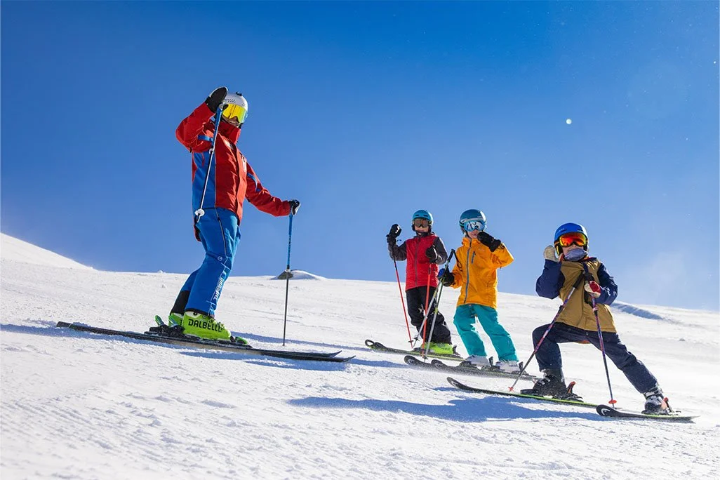 Ski instructor with three young students on the slopes at the snow