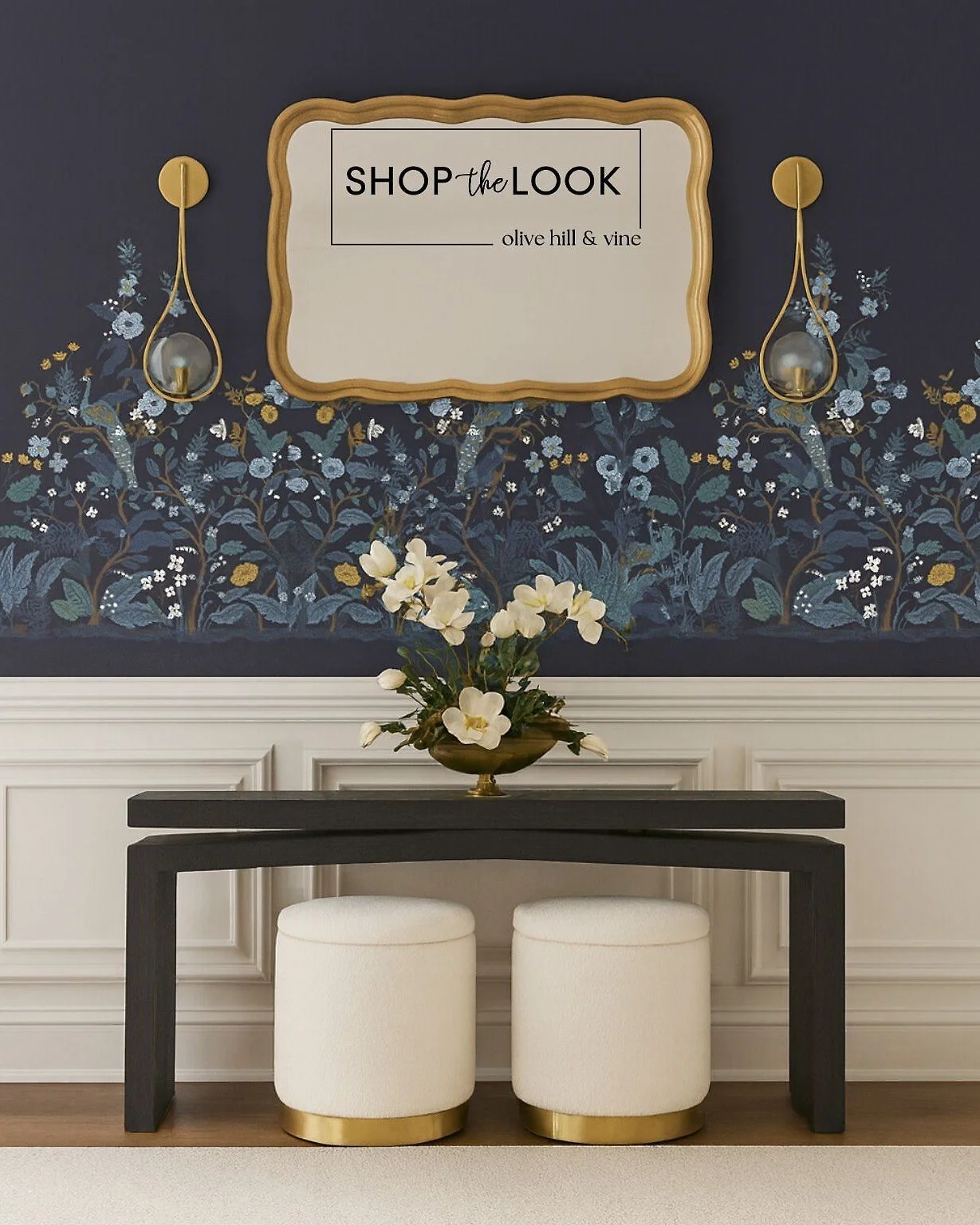 Bold navy walls with floral and peacock details bring drama to your entryway. A sleek console, ivory ottomans with gold bases, brass sconces, and a gilded mirror complete this statement look with elegance and function. 

Comment SHOP below to receive