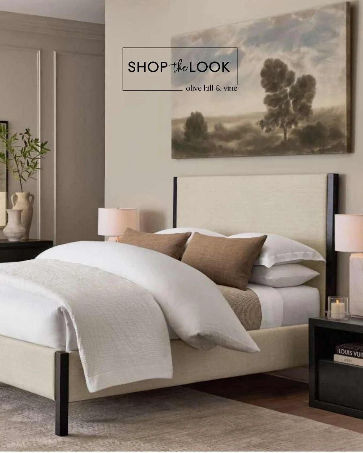 Warm neutrals meet crisp black accents in a bedroom designed to feel both relaxed and refined. The upholstered bed softens the contrast, while layered whites, rich wood tones and an oversized landscape bring warmth and depth to this timeless retreat.