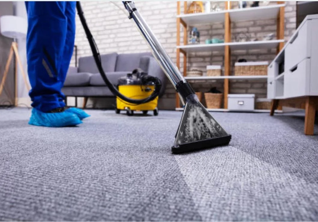 A carpet cleaning extractor cleaning a grey carpet