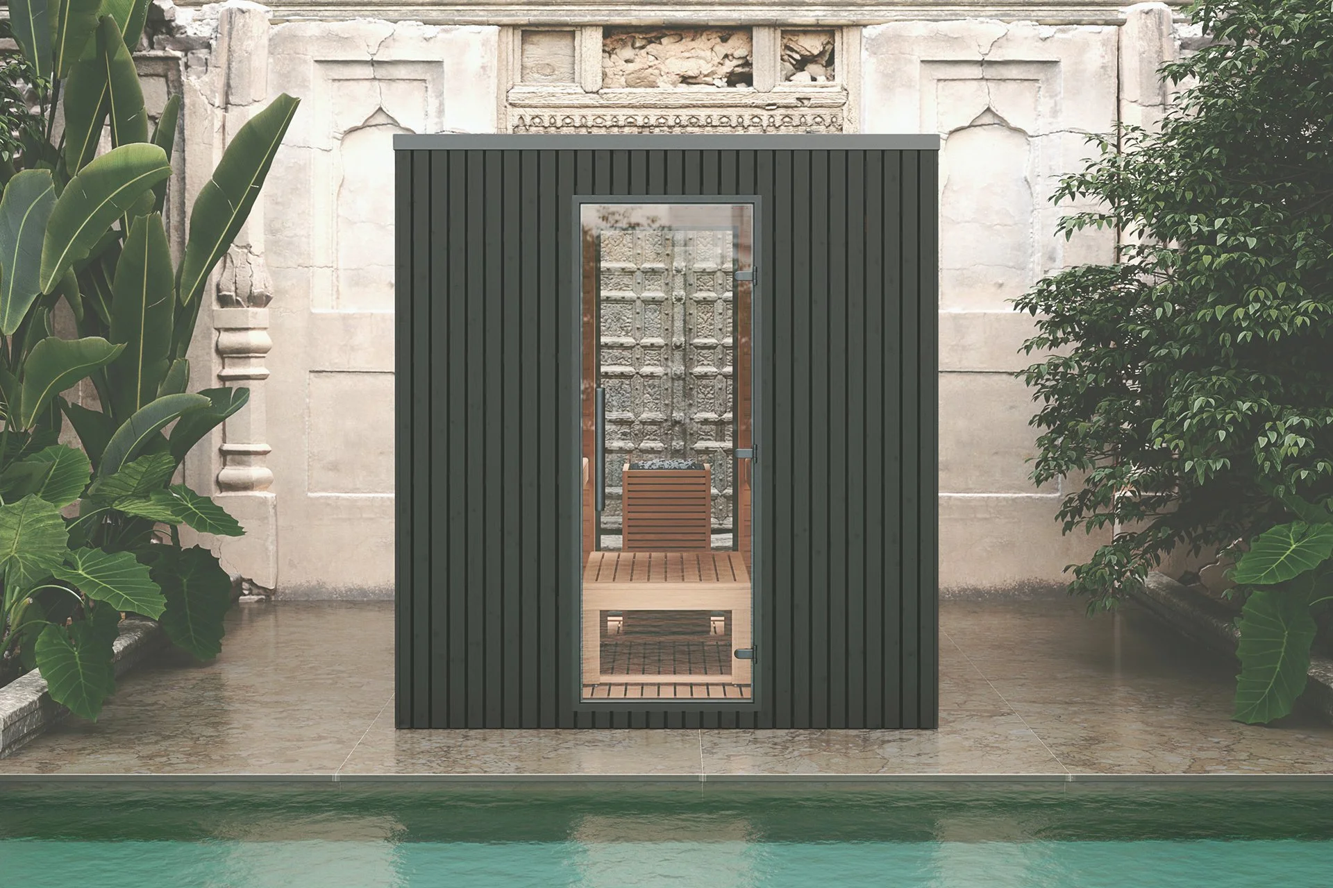 A black wooden sauna with a glass door, situated near a swimming pool, surrounded by lush green plants and ornate stone wall.