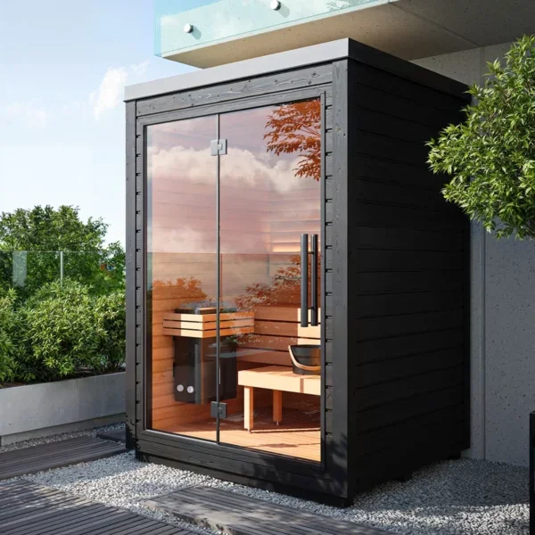 Small black wooden sauna with glass front and door, surrounded by landscaping and outdoor furniture.