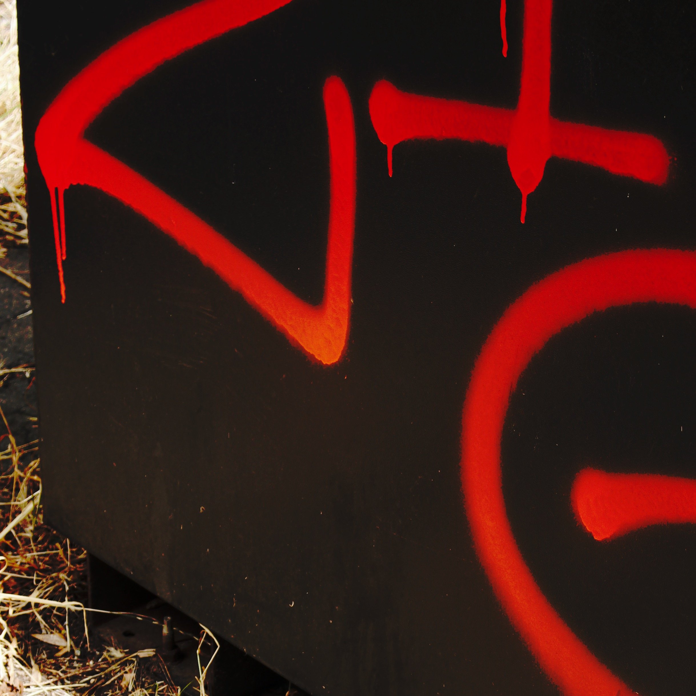 red graffiti splashed on dark utility box exterior photograph