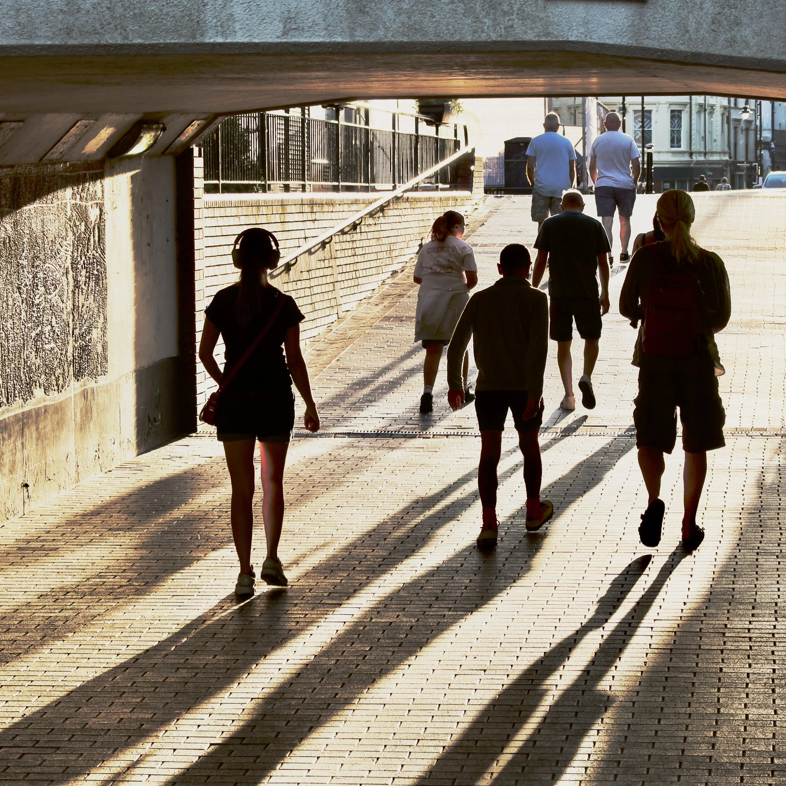 people walking through a light-filled underpass in hastings