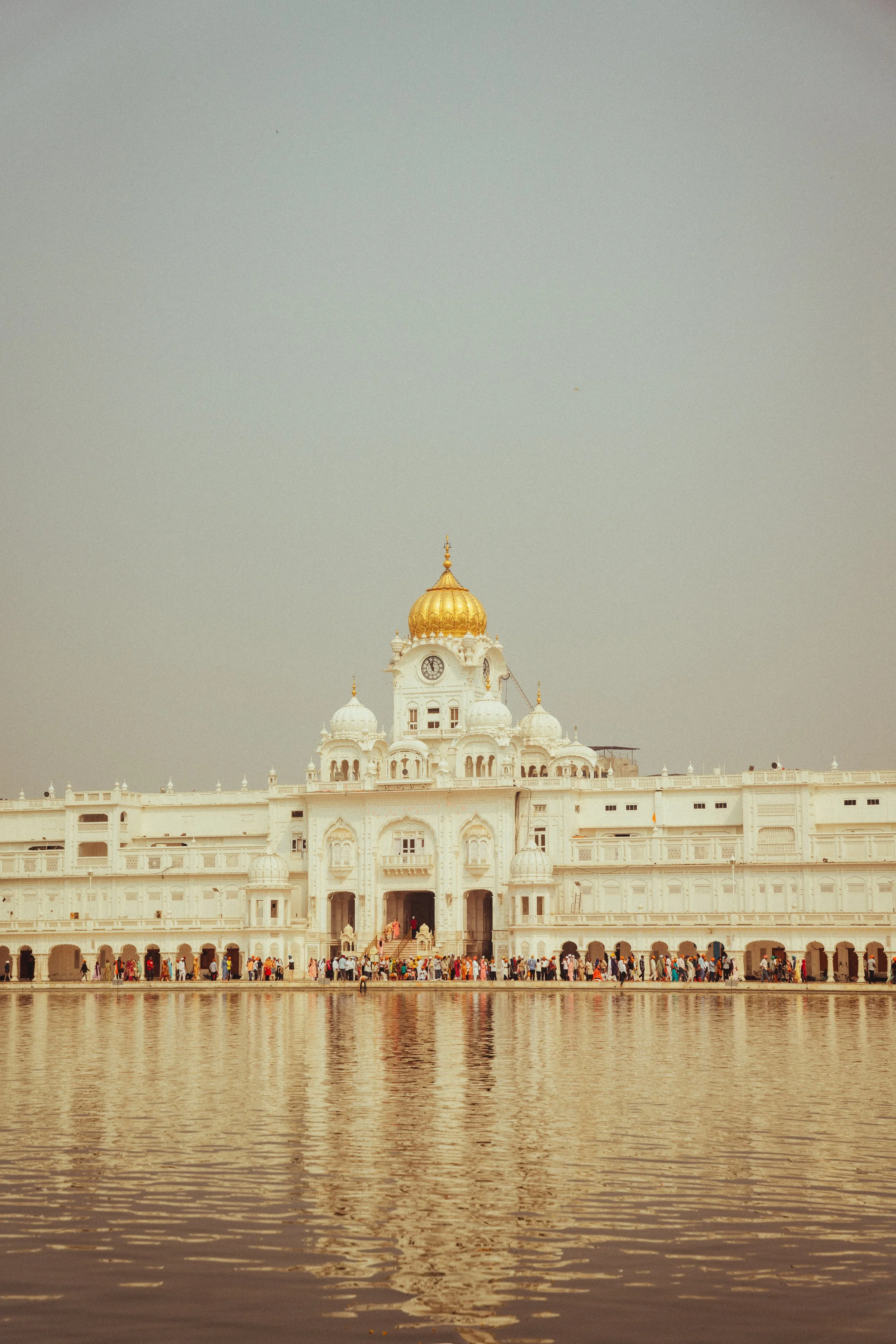 Weißes Palastgebäude mit goldener Kuppel und Wasser im Vordergrund, viele Menschen vor der Eingangshalle