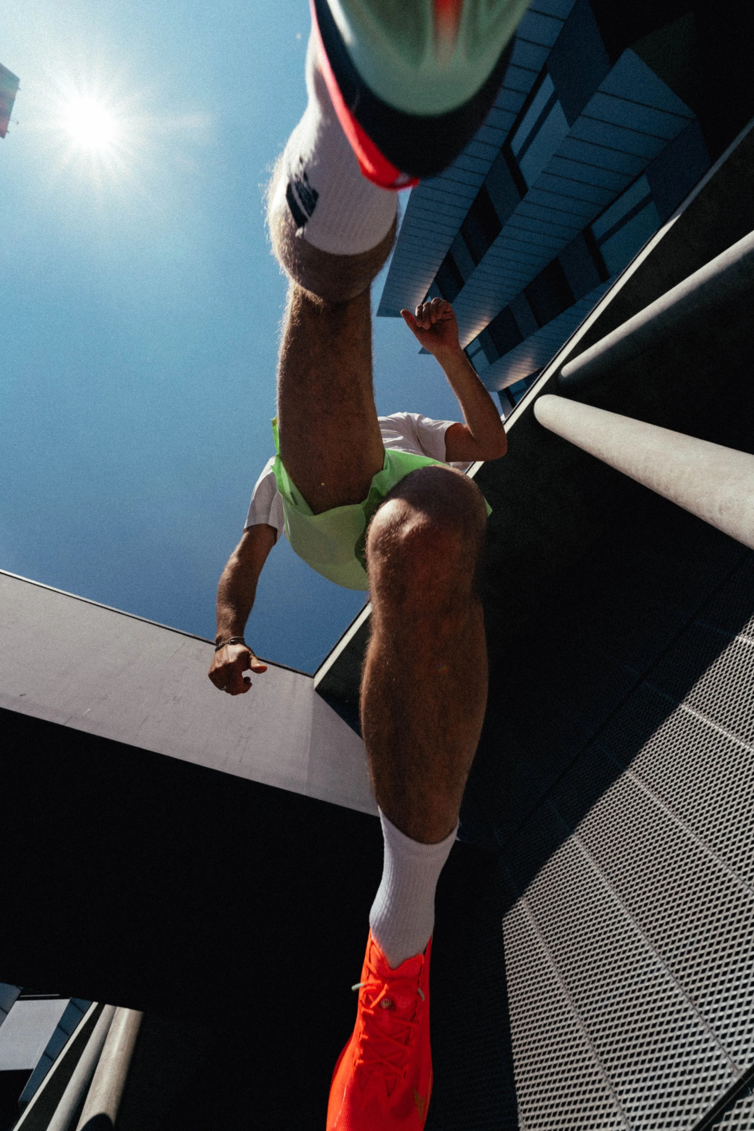 Ein Mann beim Springen auf einer Dachterrasse bei sonnigem Himmel, aufgenommen aus einer niedrigen Perspektive.