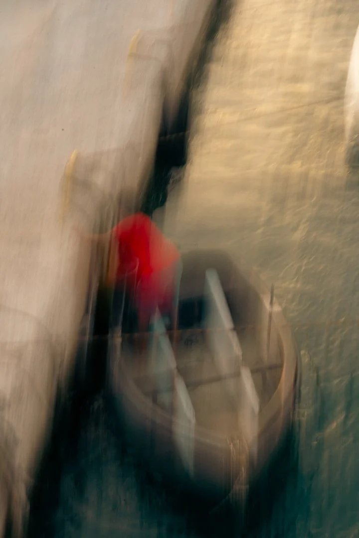 Ein verwaschener Blick auf einen Einkaufswagen mit einer Person in roter Kleidung, die nebeneinander steht, auf einem Gehweg neben einer Wand.