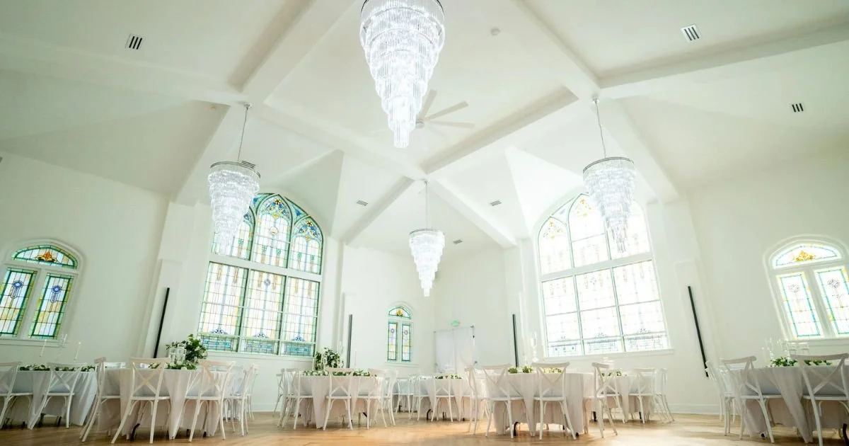 crystal chandeliers hanging above reception tables beneath original stained glass windows