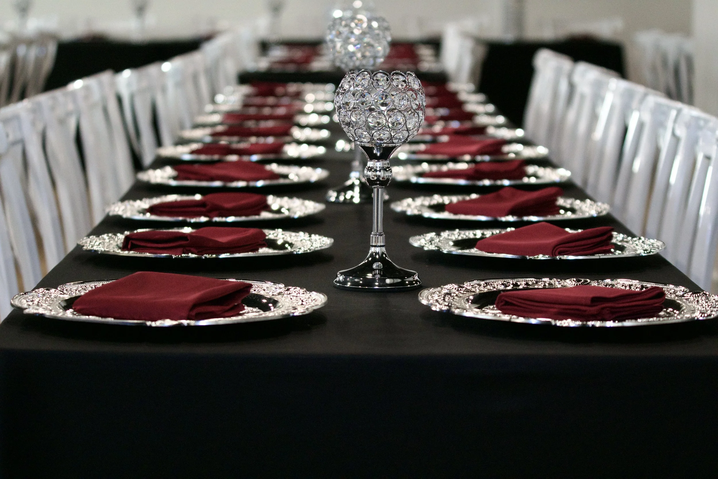 two crystal glass centerpieces lined down a long black reception table