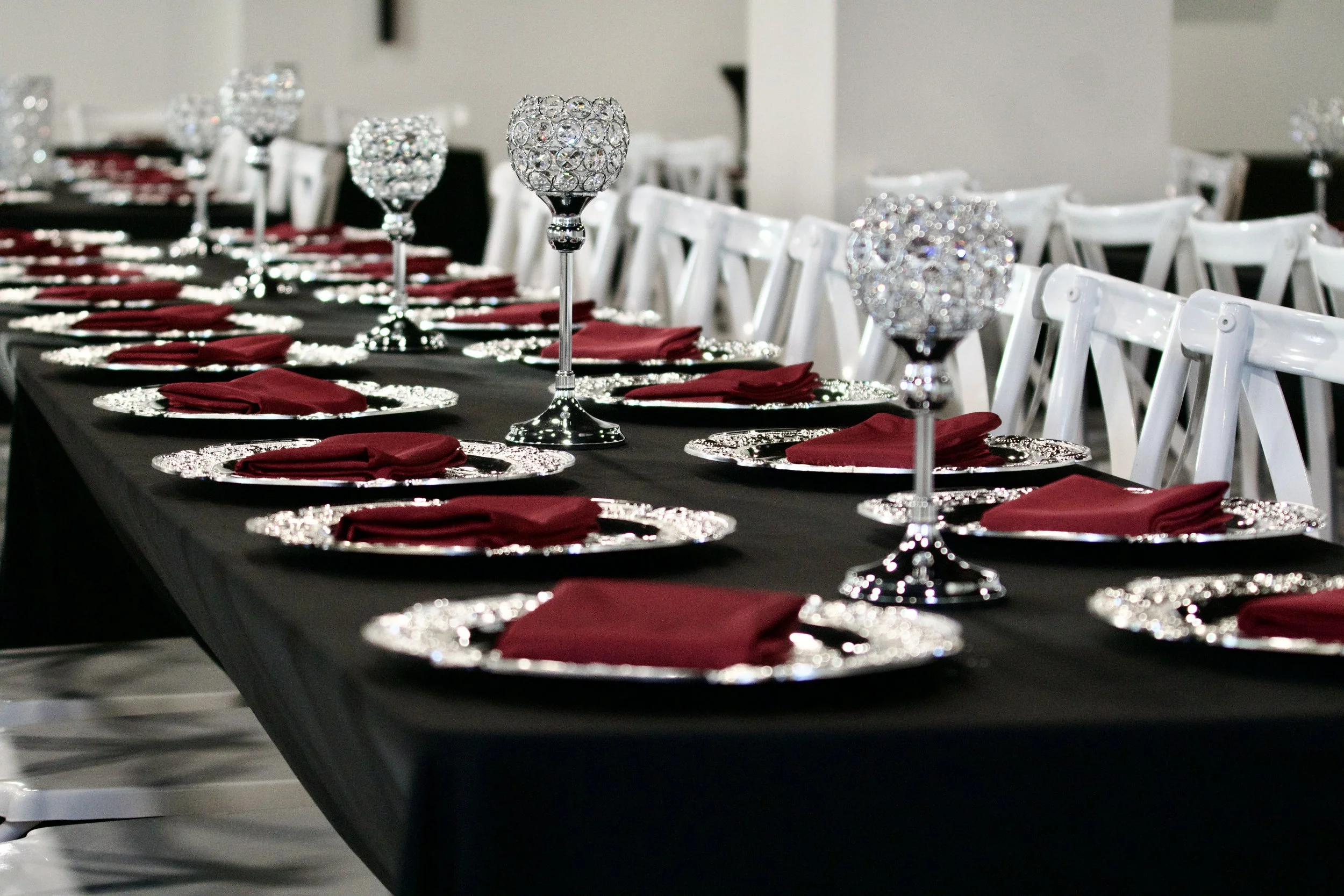 row of crystal candle holders spaced along a black linen reception table