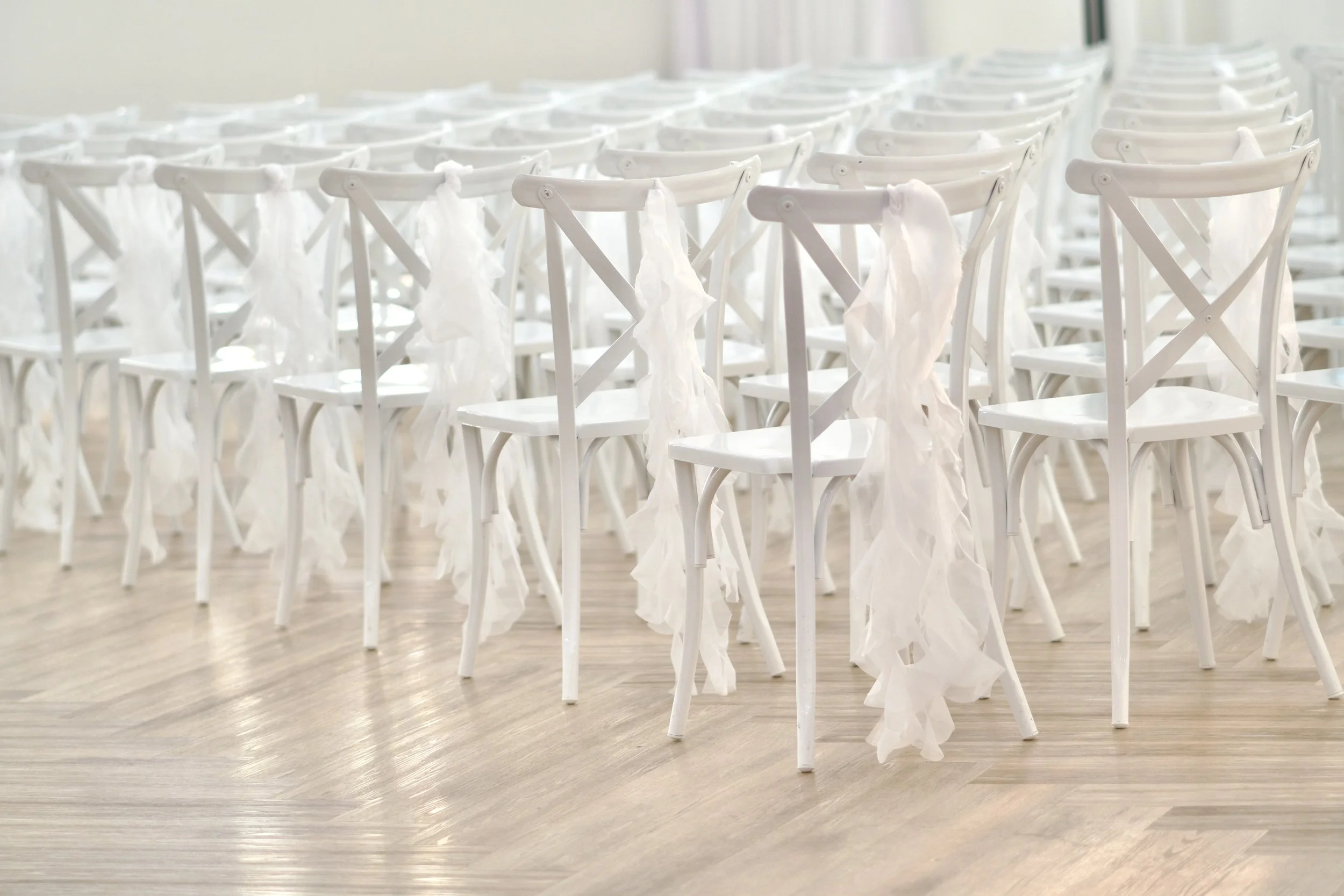 rows of white ceremony chairs with sheer drapery inside a historic church venue