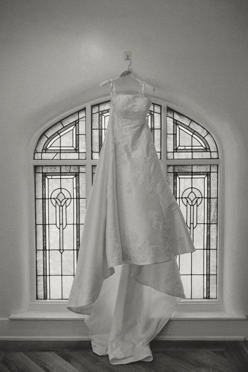 wedding-dress-hangs-in-front-of-stained-glass-windox-black-and-white.jpg