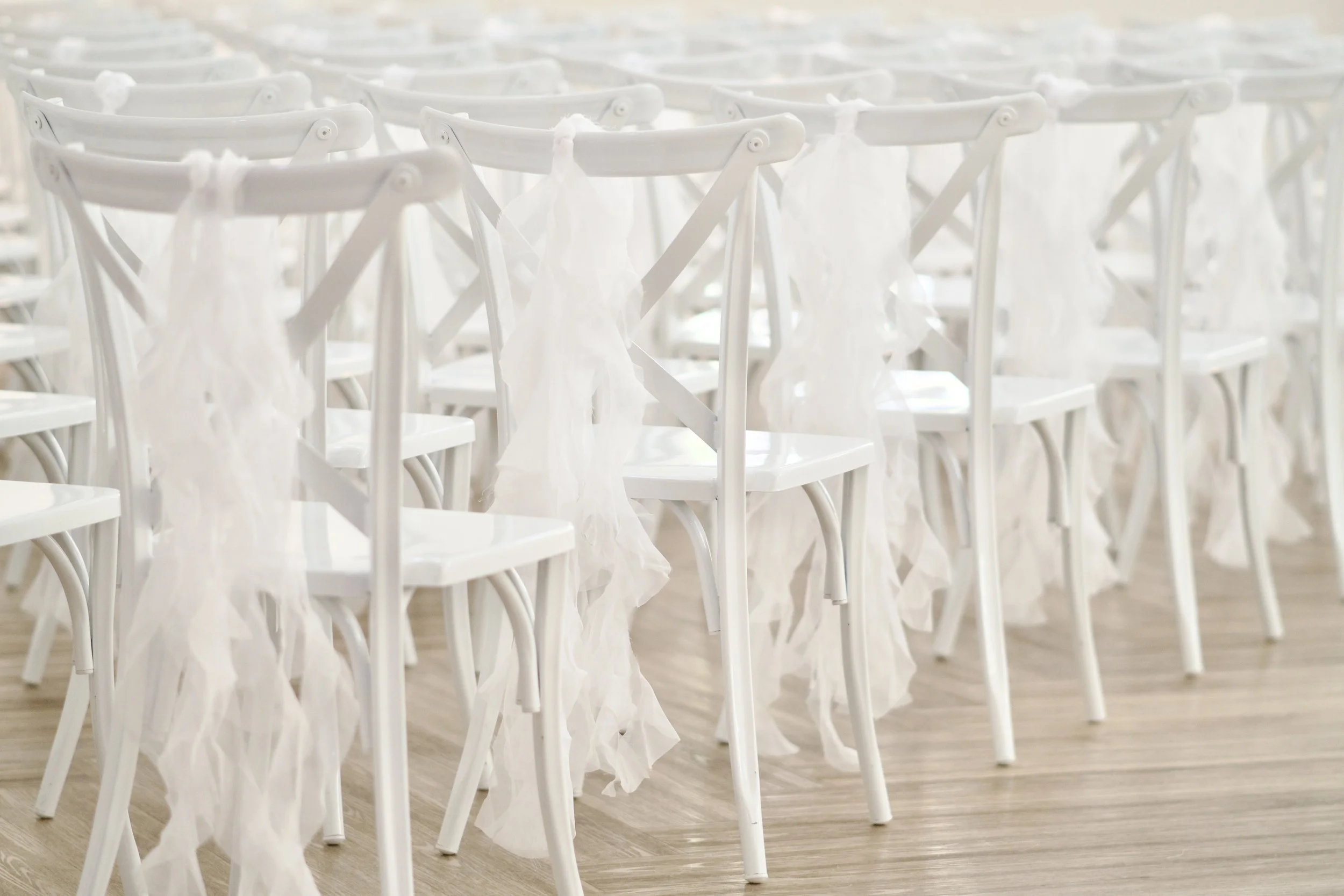 detail of sheer white drapery cascading down a row of ceremony chairs