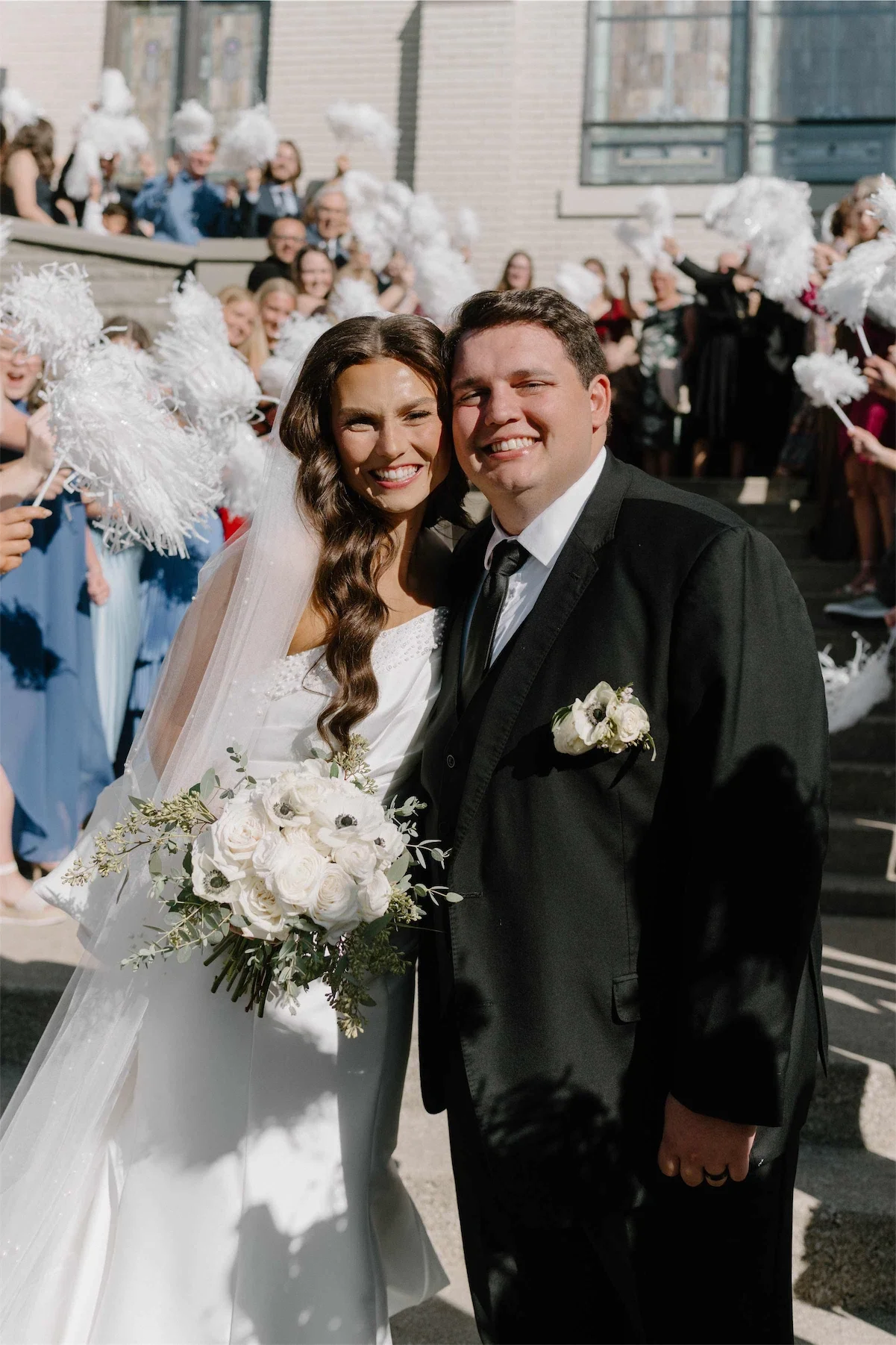 newlyweds-smiling-pom-pom-send-off-crowd.webp