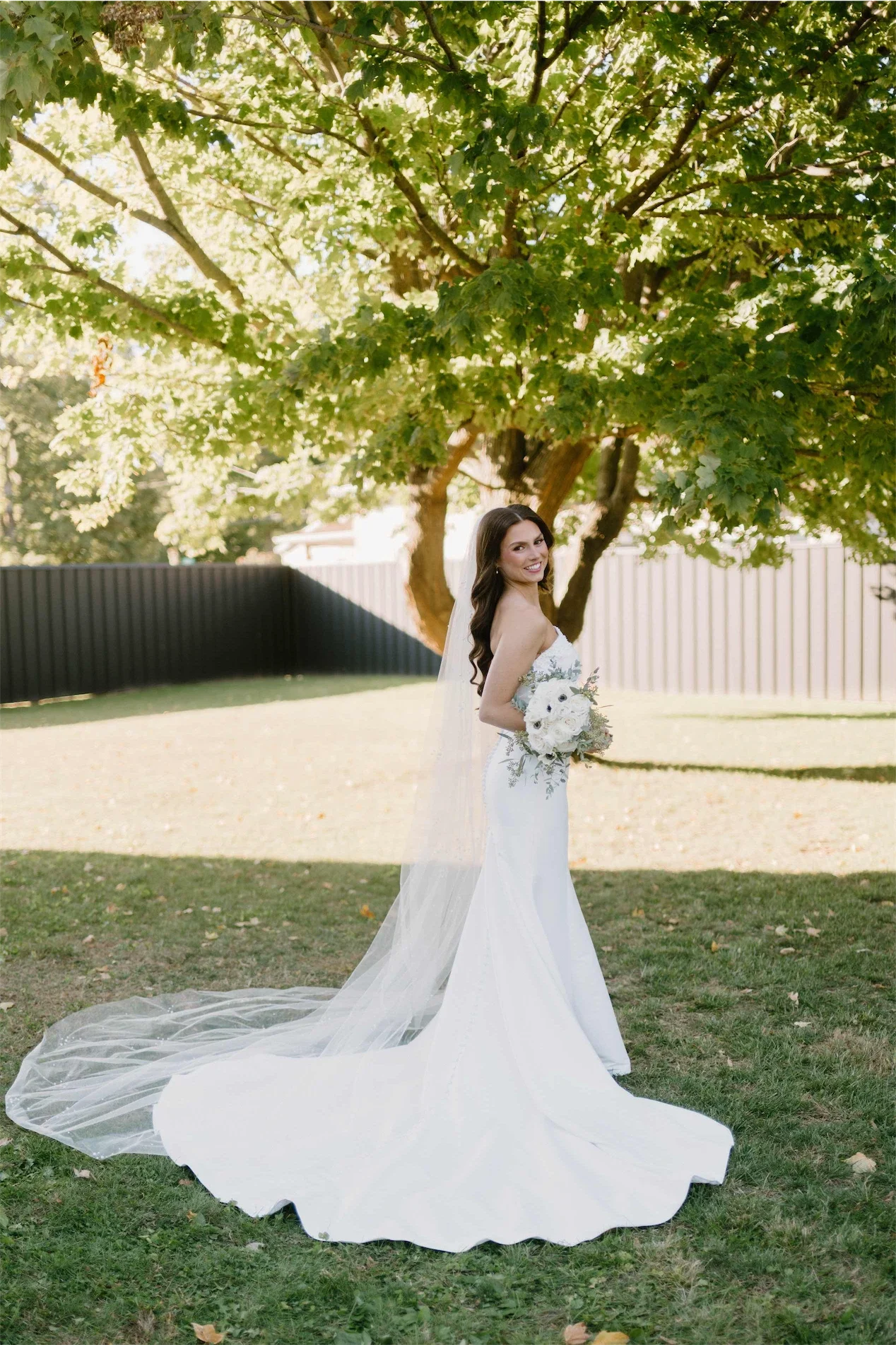 bride-looking-over-shoulder-veil-and-train-lawn.webp