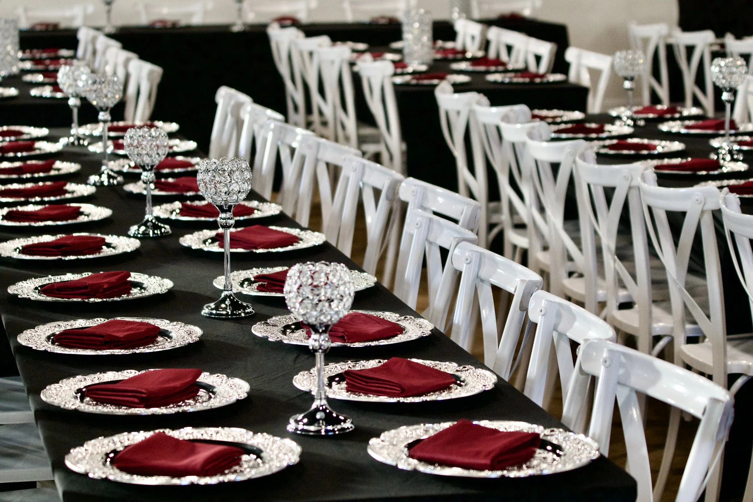 two Gatsby reception tables with crystal centerpieces and white cross back chairs