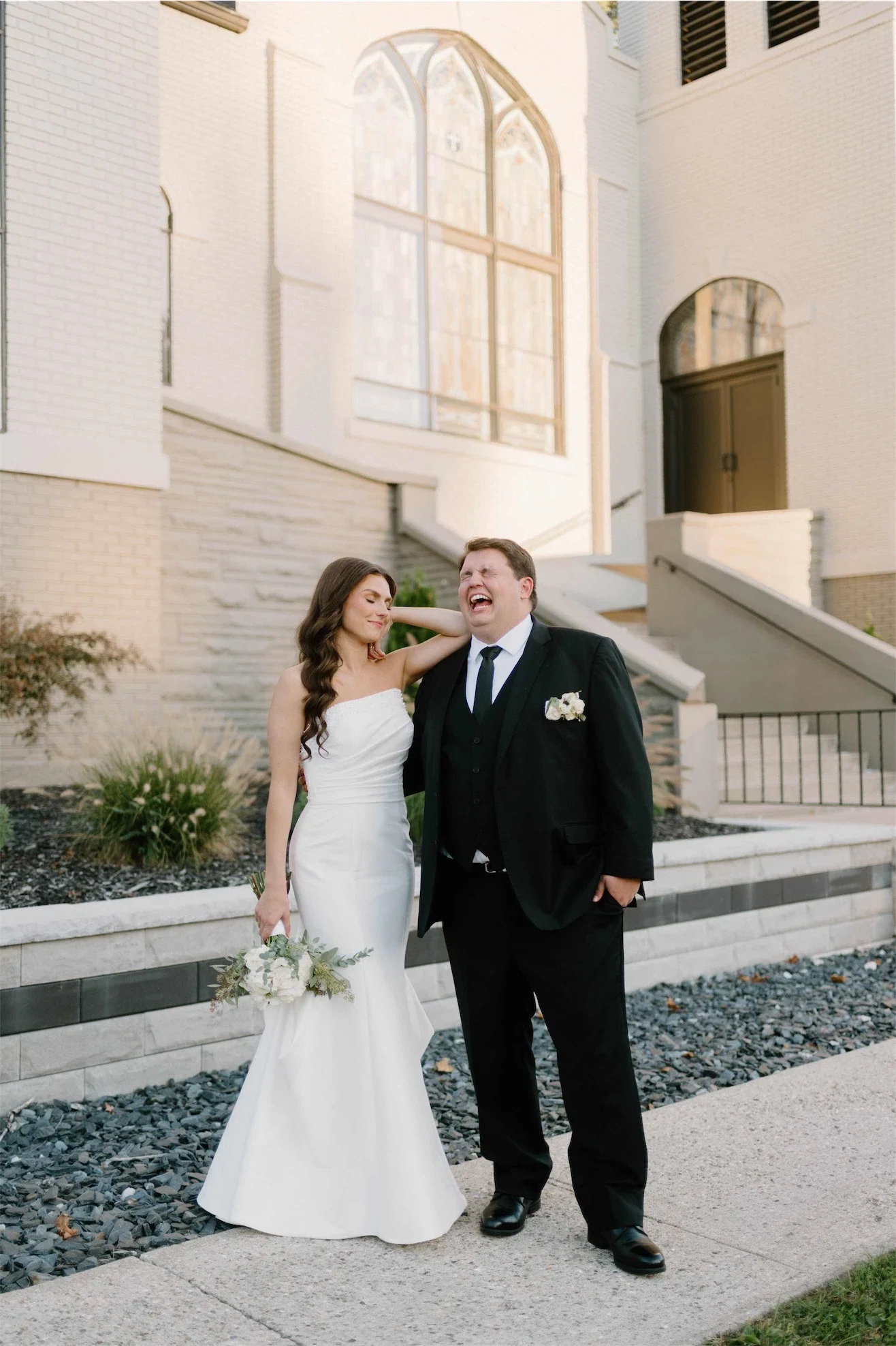 groom-laughing-bride-portrait-chapel-exterior.webp