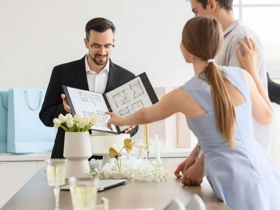 Engaged couple reviewing a wedding venue floor plan booklet with a venue coordinator during a consultation