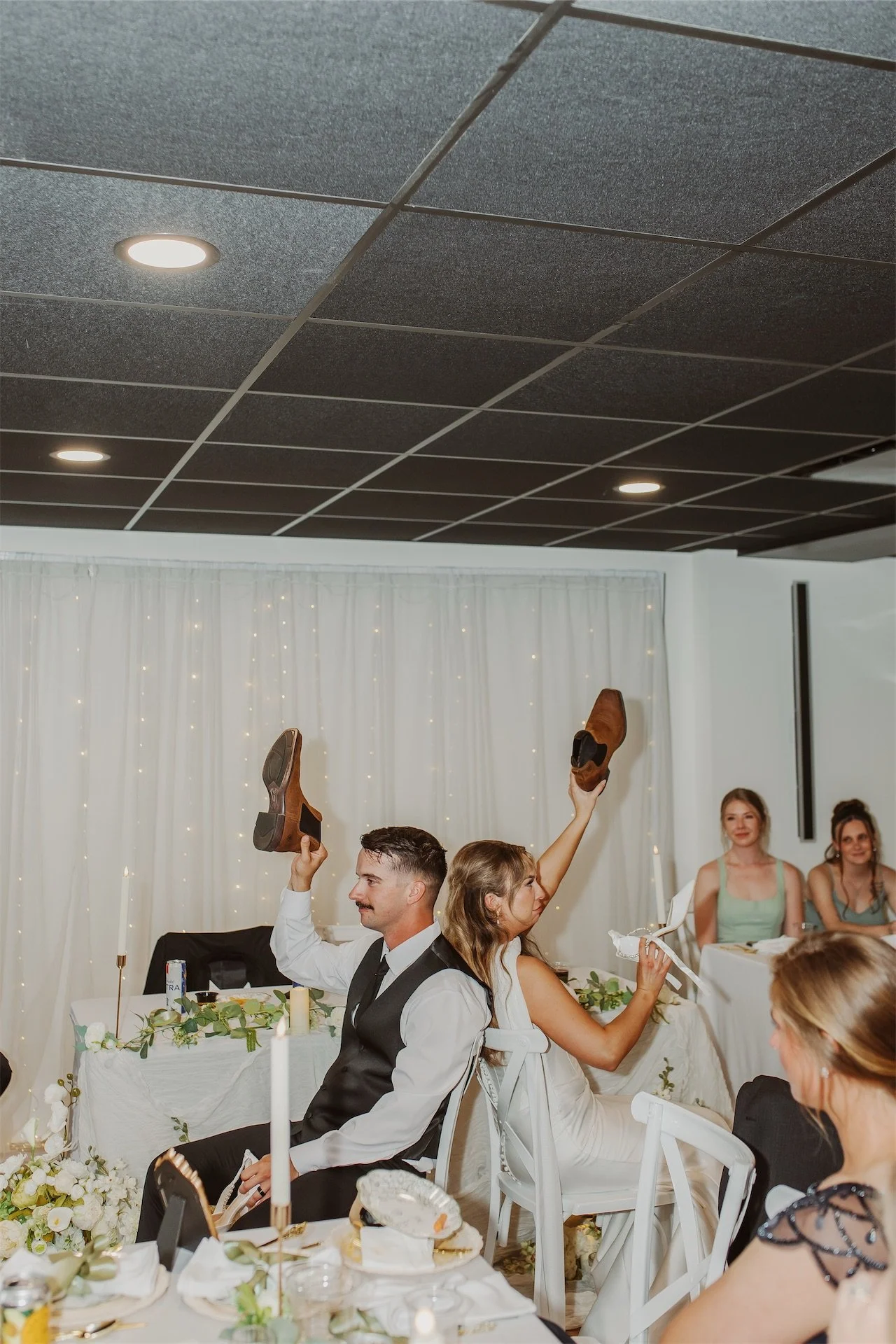 Bride and groom holding up garter and shoe during reception garter toss